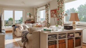 Ein gemütliches Wohnzimmer mit einer Couch, einem Couchtisch mit Büchern und einem Bücherregal.