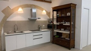 Een moderne keuken met witte kastjes, een ingebouwde oven en een houten kastje met servies.