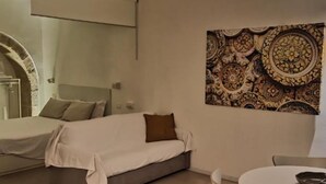 Een moderne slaapkamer met een bed, een kleine bank, een ronde tafel en een decoratief wandtapijt.