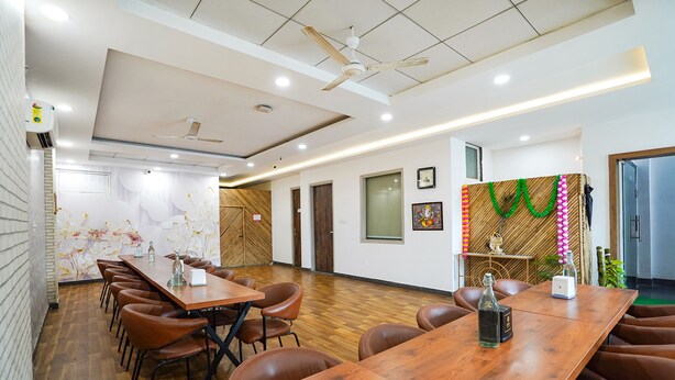 A conference room with a long wooden table, brown leather chairs, and a ceiling fan. - Fabhotel Prime Culture (Noida)