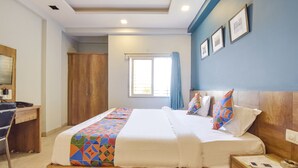 A hotel room with a bed, a desk, a wardrobe, and a window with curtains. - Fabhotel Rush Imperial (Indore)