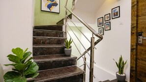 Un escalier avec des rampes en métal, des plantes en pot et des œuvres d’art encadrées accrochées aux murs.