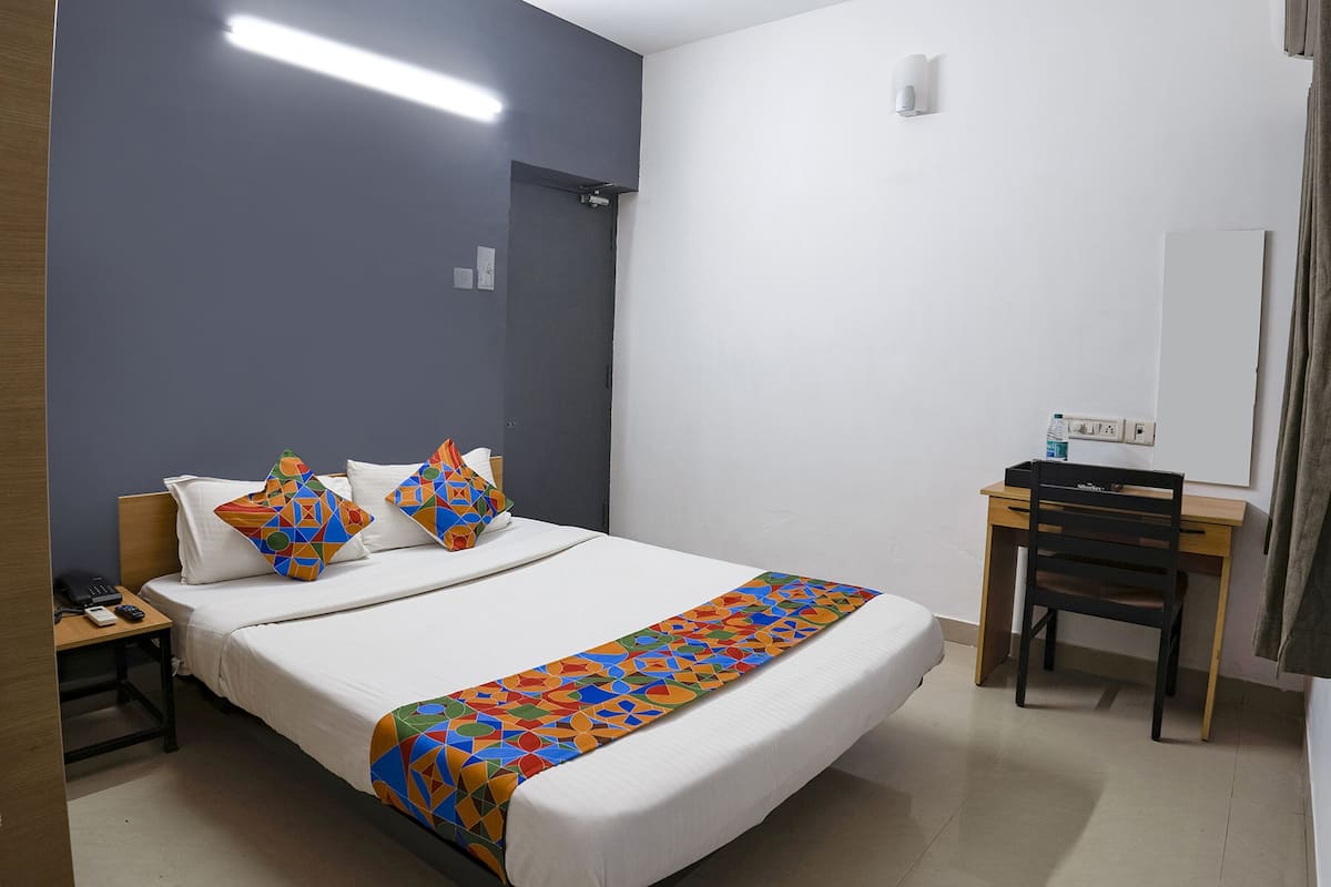 Ein Hotelzimmer mit Bett, Schreibtisch, Stuhl, Telefon und Steckdose.