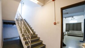 A staircase with a handrail leading to a landing, a light switch, and a power outlet on the wall. - Fabhotel Bella Vagues (Tirupporur)