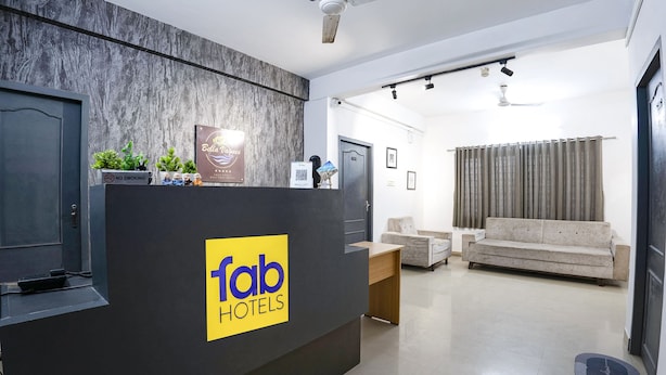 A hotel reception area with a modern design, including a reception desk, a sofa, and a ceiling fan. - Fabhotel Bella Vagues (Tirupporur)