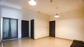 A spacious room with a large window, a door, and a ceiling light. - Fabhotel Bella Vagues (Tirupporur)