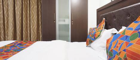A hotel room with a bed, a wardrobe, and a bathroom visible through a glass door.