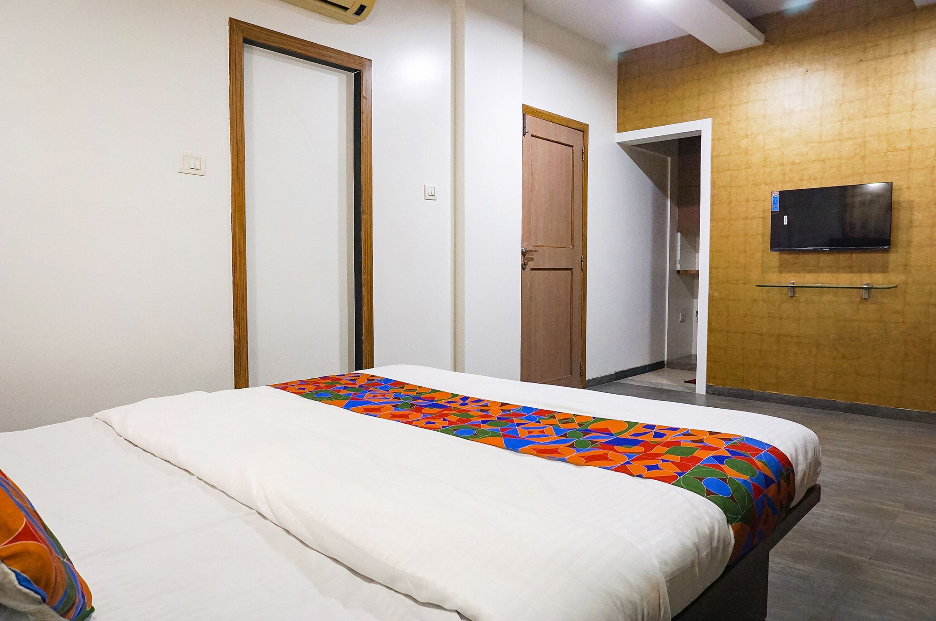 Ein Hotelzimmer mit einem Bett, einem an der Wand befestigten Fernseher und einer Holztür.