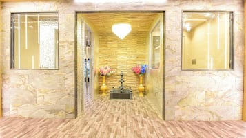 A hallway with marble walls, a wooden floor, and a chandelier.