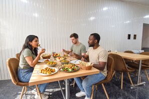 A group of people dining at a table with various dishes, in a room with a modern design and a white wall. - Fabhotel Pearl Square (Jaipur)