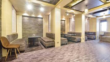 A spacious lounge area with multiple seating options, including sofas and a chair, arranged around a central table.