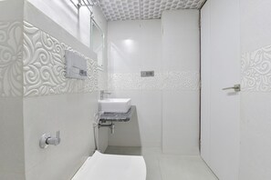 Un baño con un lavamanos blanco, un espejo y una zona de ducha.