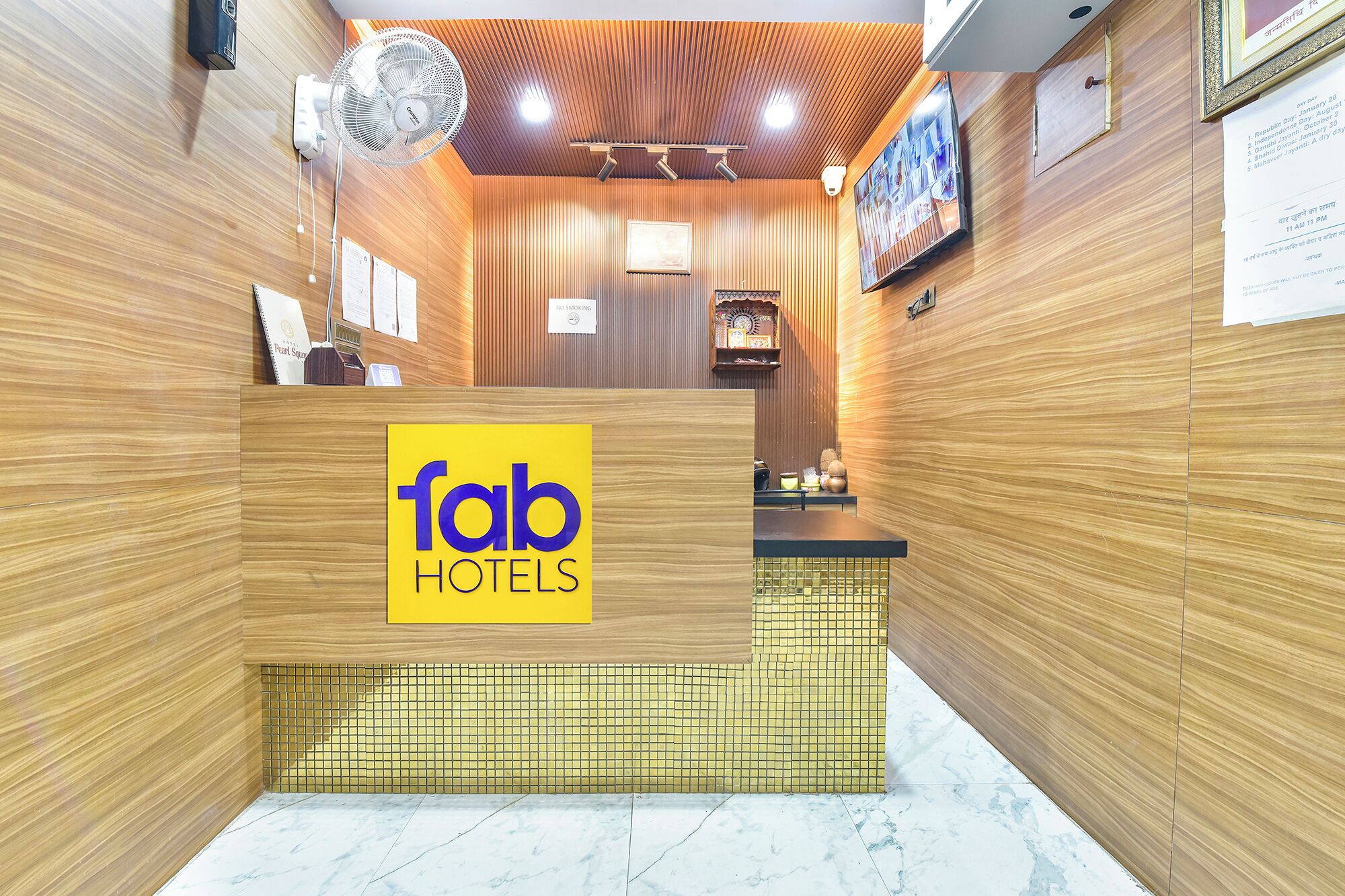 A hotel reception area with a wooden interior, a reception desk, and a wall-mounted television.