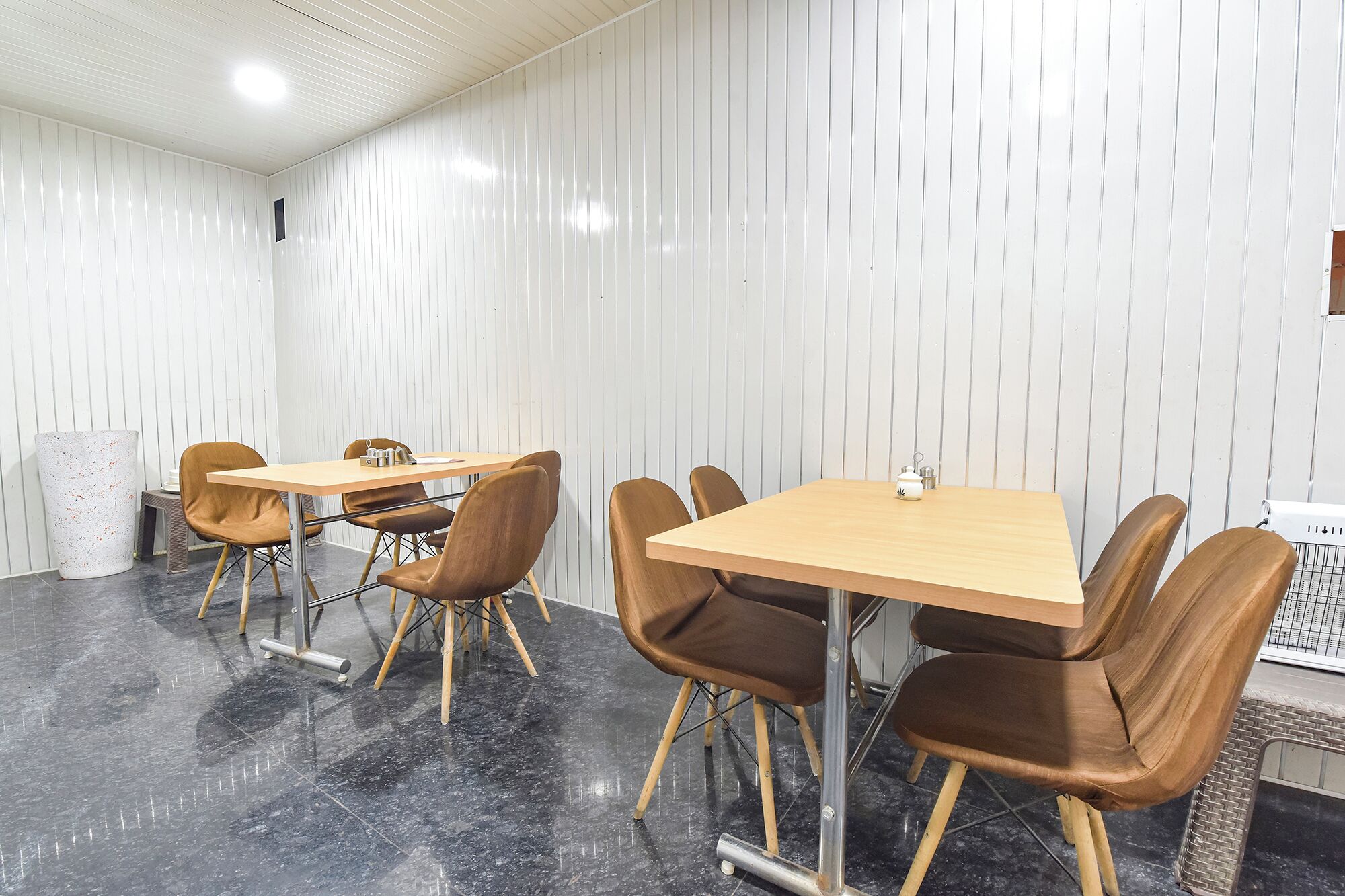 A conference room with a wooden table and brown chairs, white walls, and a tiled floor.