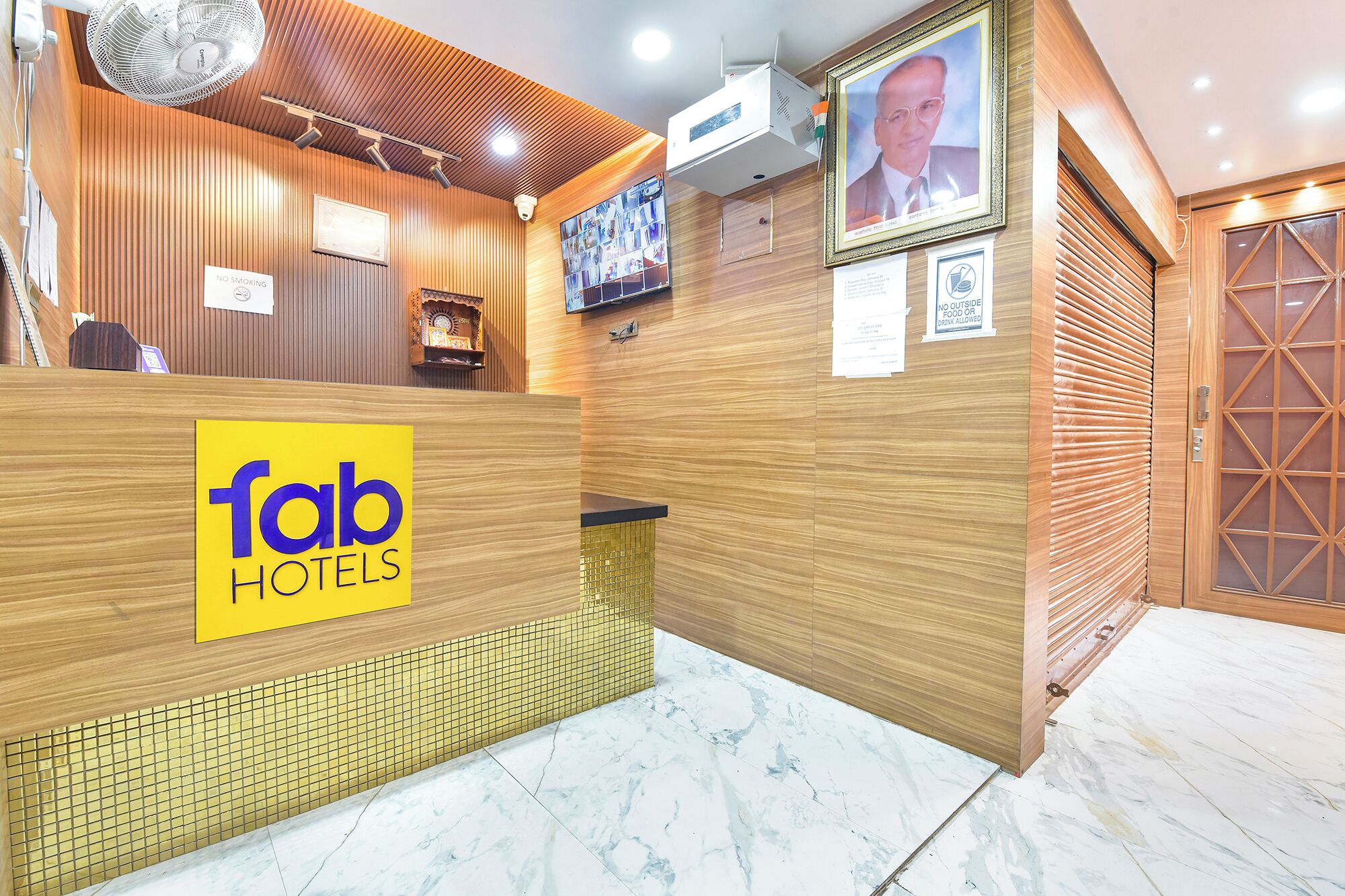 A reception desk with a 'fab hotels' sign, a television screen, and a 'no smoking' sign.