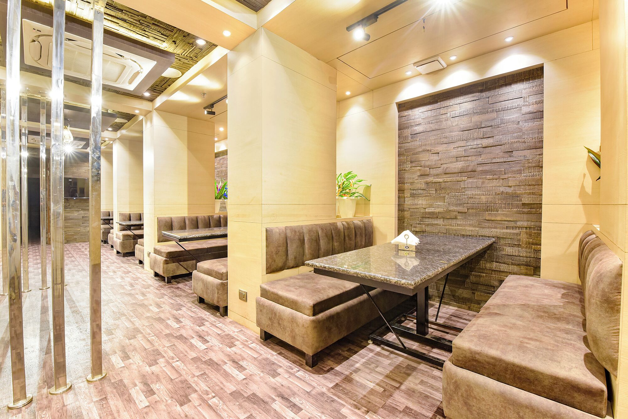 A modern interior with seating arrangements, a stone accent wall, and a wooden floor.