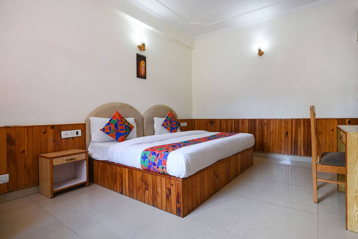 A wooden bed with a colorful blanket, a nightstand, and a wooden chair.