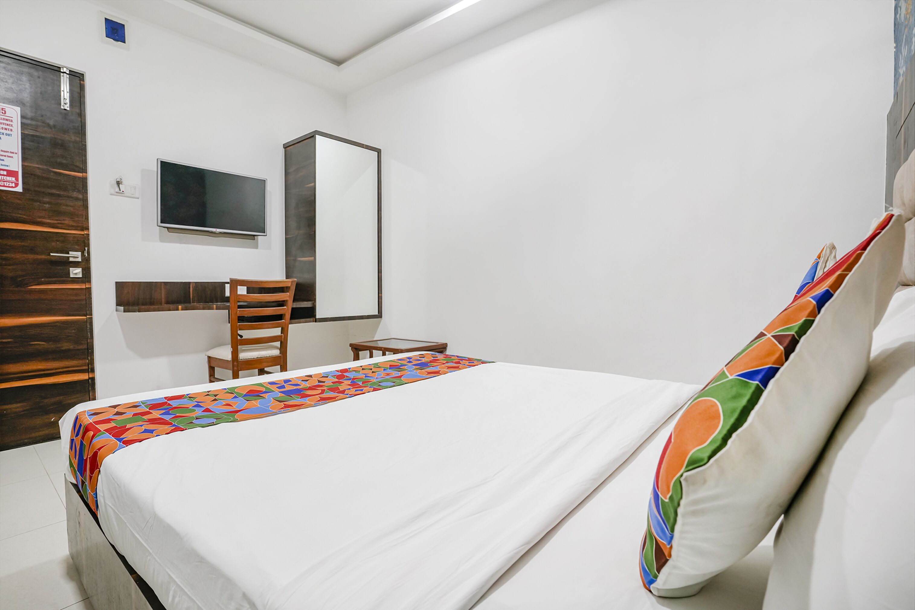 Ein Hotelzimmer mit Bett, Schreibtisch, Stuhl, Fernseher und Spiegel.