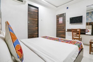 A hotel room with a bed, a wooden wardrobe, a television, and a small table. - Fabhotel Elvis Inn (Mumbai)
