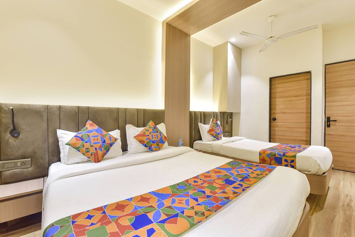 A hotel room with two beds, a wooden headboard, a ceiling fan, and a wooden door.
