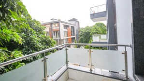 A modern building with a glass railing and a view of neighboring structures. - Fabhotel Silver Tree (Gurugram)