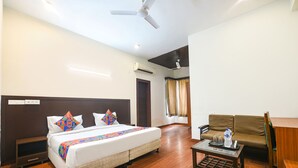 A hotel room with a bed, a sofa, a coffee table, and a ceiling fan. - Fabhotel Silver Tree (Gurugram)