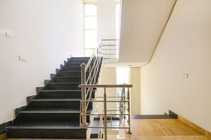 A staircase with a metal handrail, leading to a landing with a wooden floor. - Fabhotel Silver Tree (Gurugram)