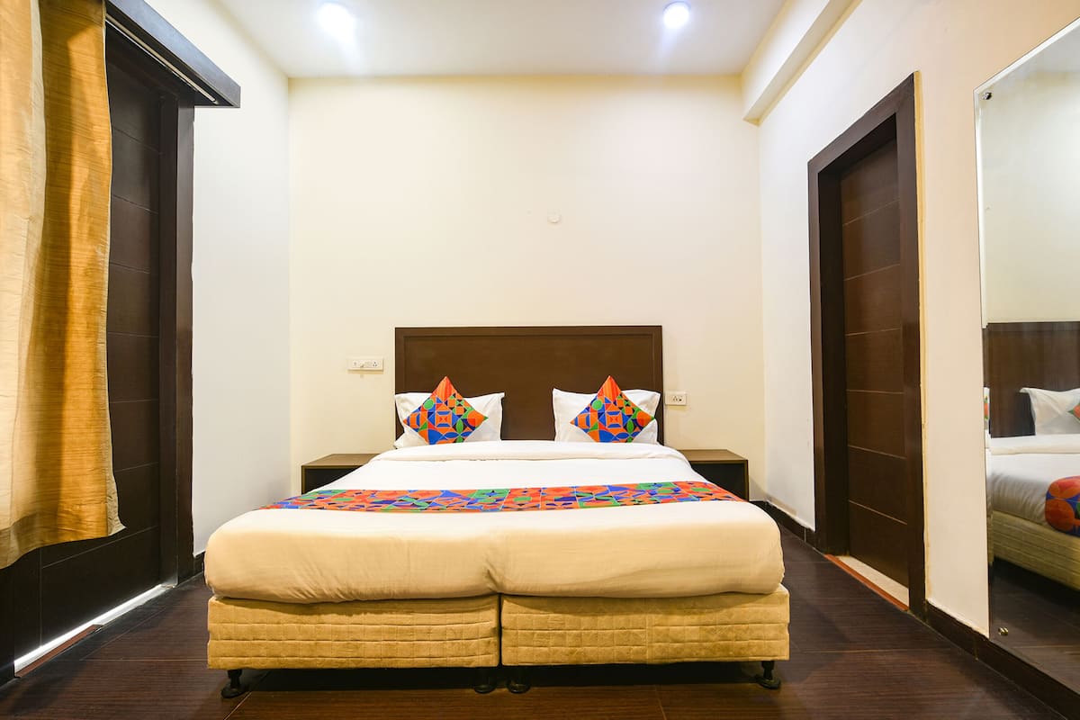 A hotel room with a large bed, two pillows, a nightstand, and a mirror.