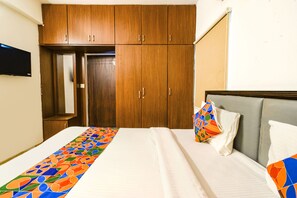A hotel room with a bed, a wooden wardrobe, and a television on the wall. - Fabhotel Rs (Hyderabad)
