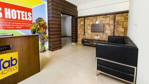 A hotel reception area with a reception desk, a seating area, and a stone wall. - Fabhotel Rs (Hyderabad)