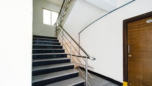 A staircase with metal railings leading to a wooden door with a number plate. - Fabhotel Rs (Hyderabad)