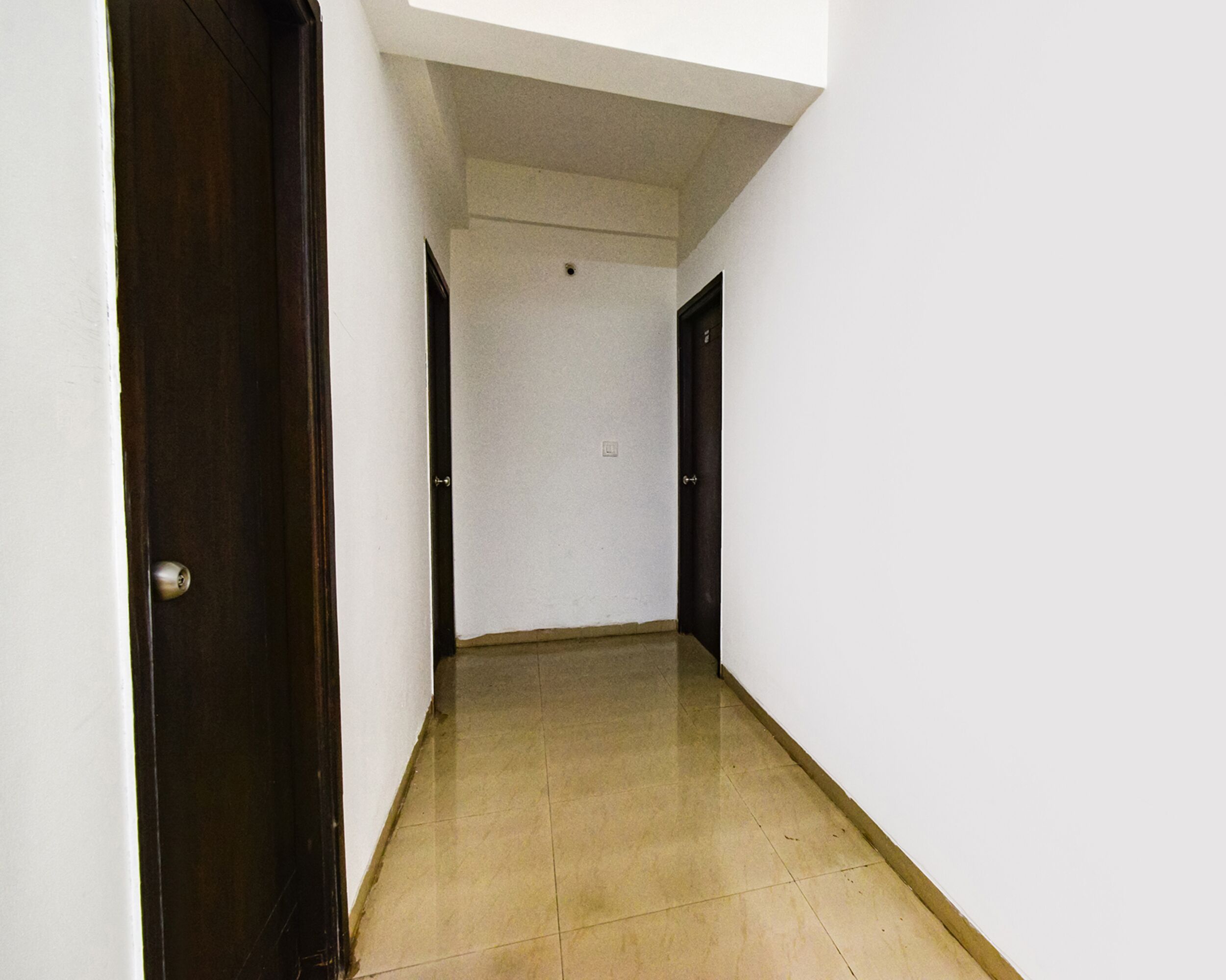 A narrow hallway with white walls and a tiled floor.