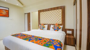 A hotel room with a large bed, a tufted headboard, and a colorful bedspread. - Fabhotel Darshan Adobe (Coimbatore)