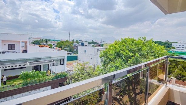 A residential area with modern buildings, a balcony with a glass railing, and a view of the sky and clouds. - Fabhotel Darshan Adobe (Coimbatore)