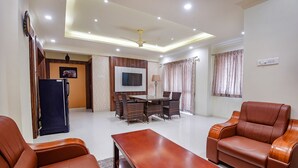 A living room with a sofa, coffee table, TV, and dining area. - Fabhotel Darshan Adobe (Coimbatore)