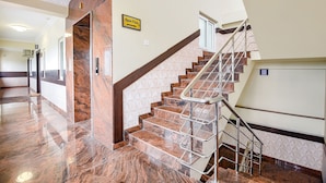 A modern hotel lobby with a marble staircase, a sign indicating the open floor, and a clean, well-lit interior. - Fabhotel Darshan Adobe (Coimbatore)