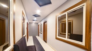 A hallway with a bench, wooden doors, and patterned wall tiles. - Fabhotel Dream Inn (Bhopal)