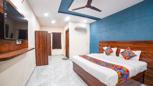 A bedroom with a bed, a ceiling fan, a TV mounted on the wall, and a wardrobe. - Fabhotel Dream Inn (Bhopal)
