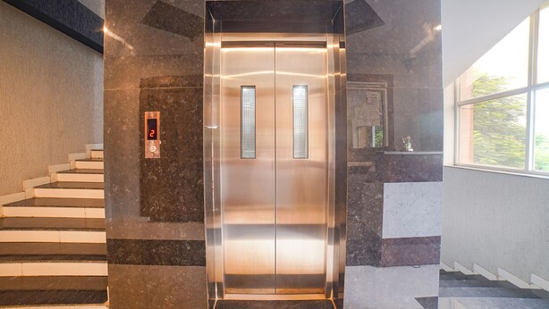 An elevator in a building with marble walls and a staircase. - Fabhotel Dream Inn (Bhopal)