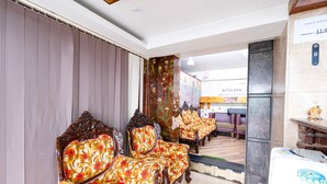 A hotel lobby with a check-in counter, a coffee shop, and a seating area with patterned chairs. - Fabhotel Lailas County (Puducherry)