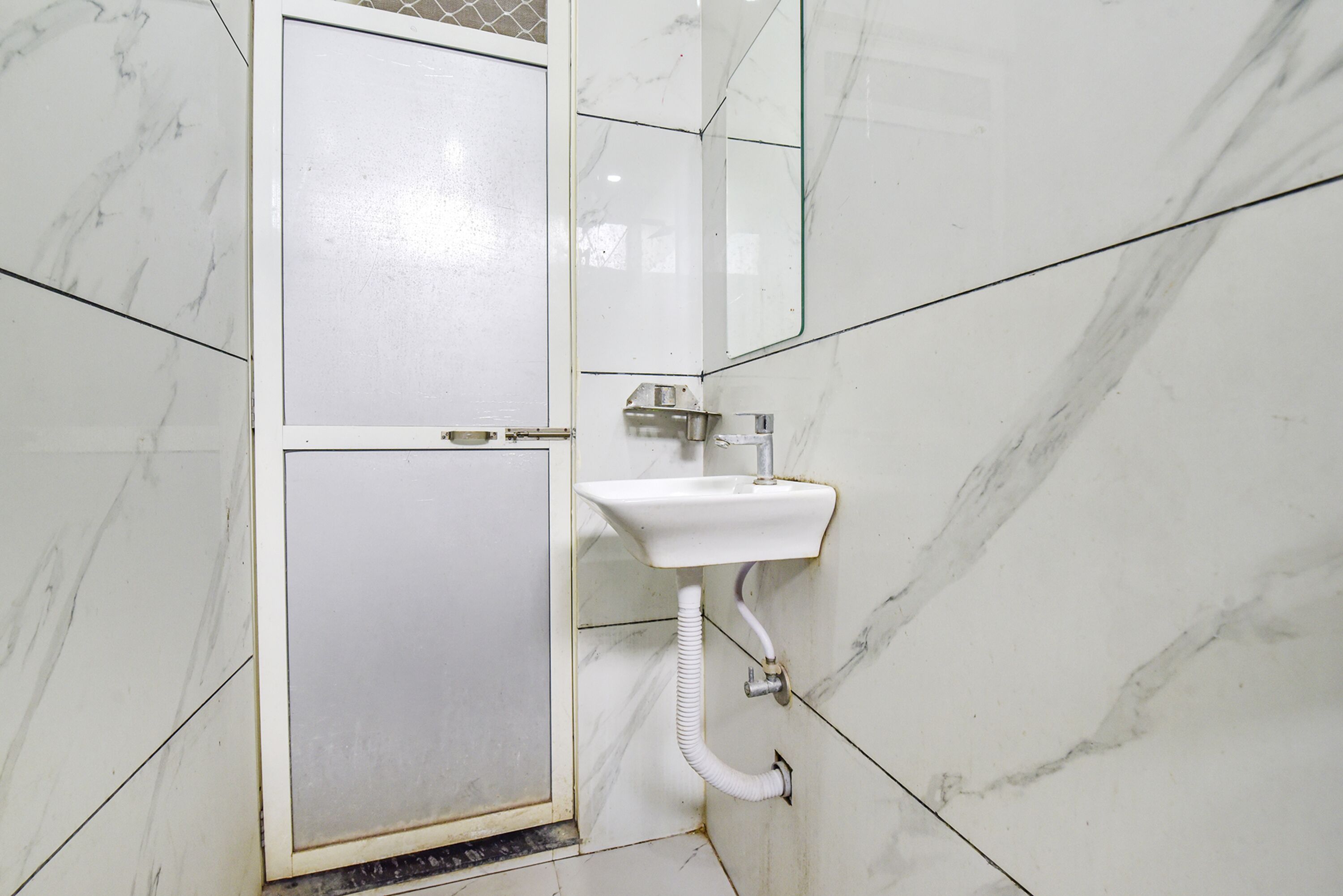 A bathroom with a white toilet, a sink, and a mirror.