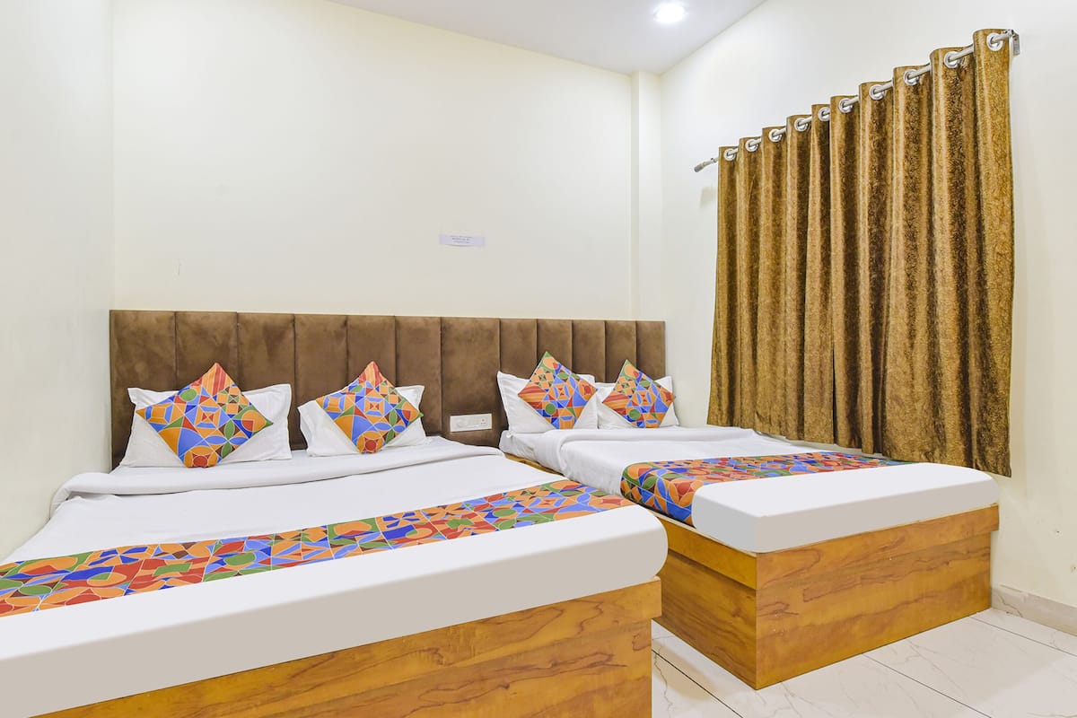 A double bed with a wooden headboard, two pillows, and a colorful bedspread.