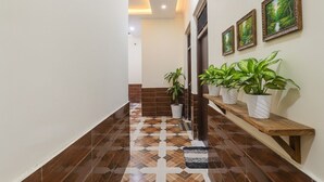 Un pasillo con piso estampado, plantas en macetas e imágenes enmarcadas en la pared.