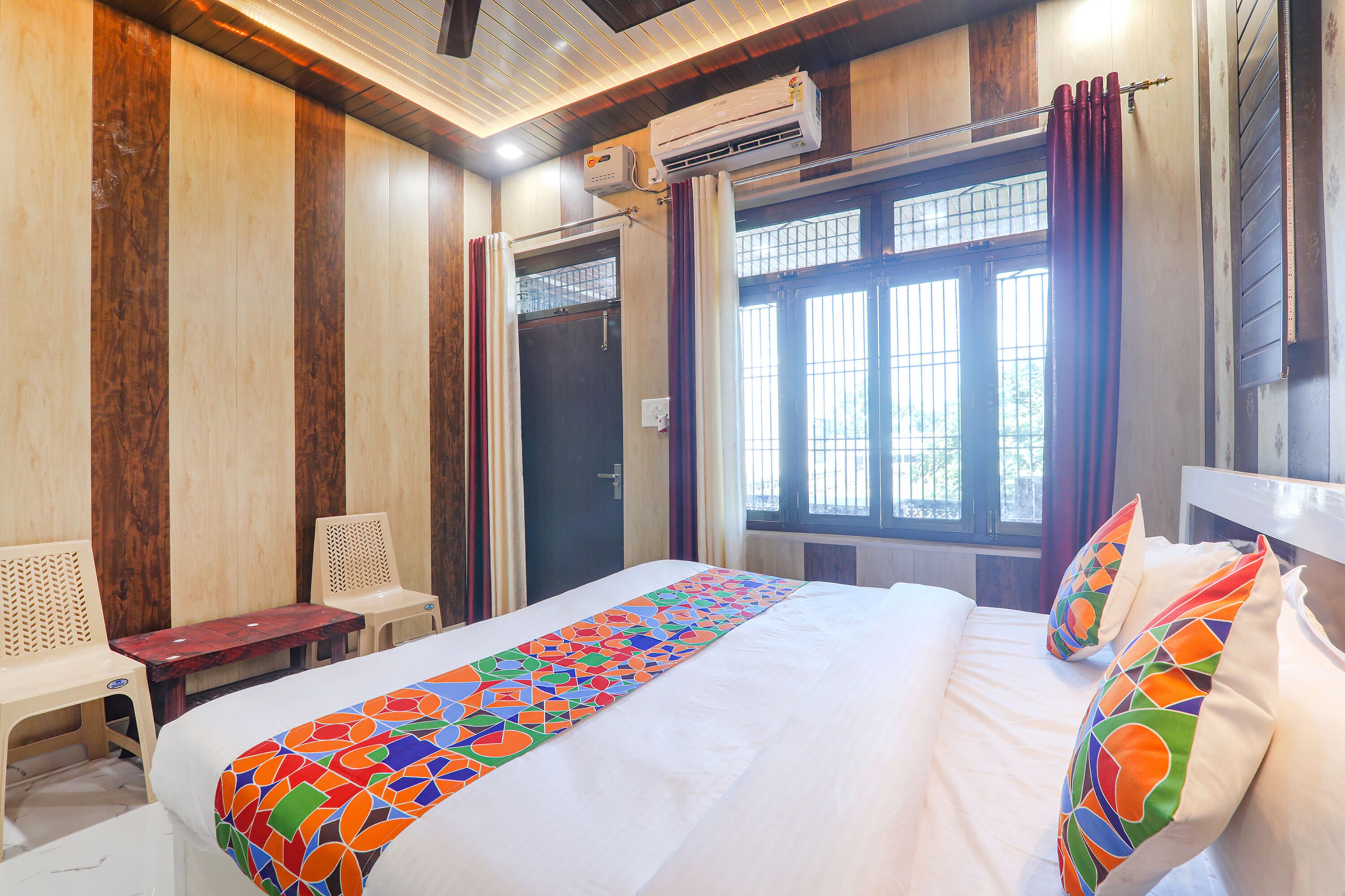 A hotel room with a bed, a window with curtains, a desk, and a chair.