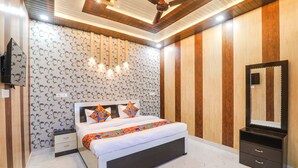 Un dormitorio moderno con una cama grande, un armario de madera, un espejo y un televisor montado en la pared.