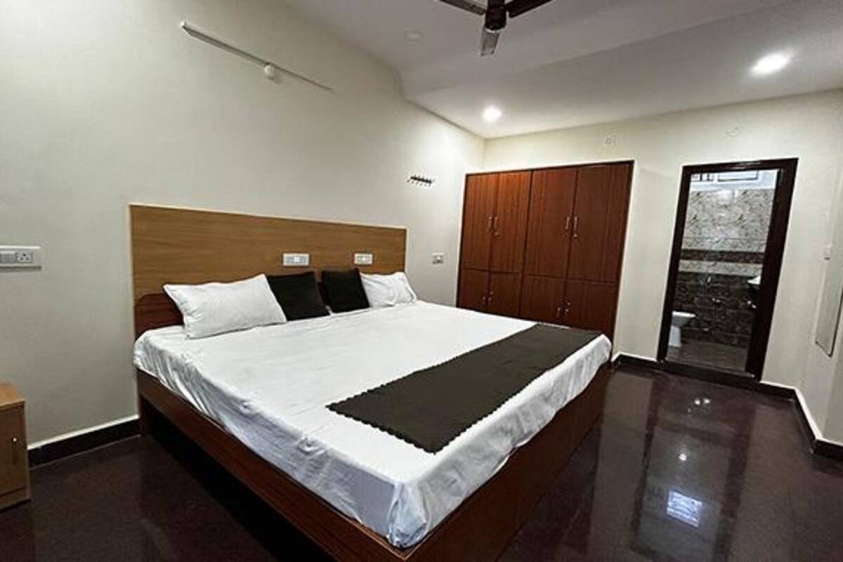 A bedroom with a large bed, wooden headboard, and a wardrobe.