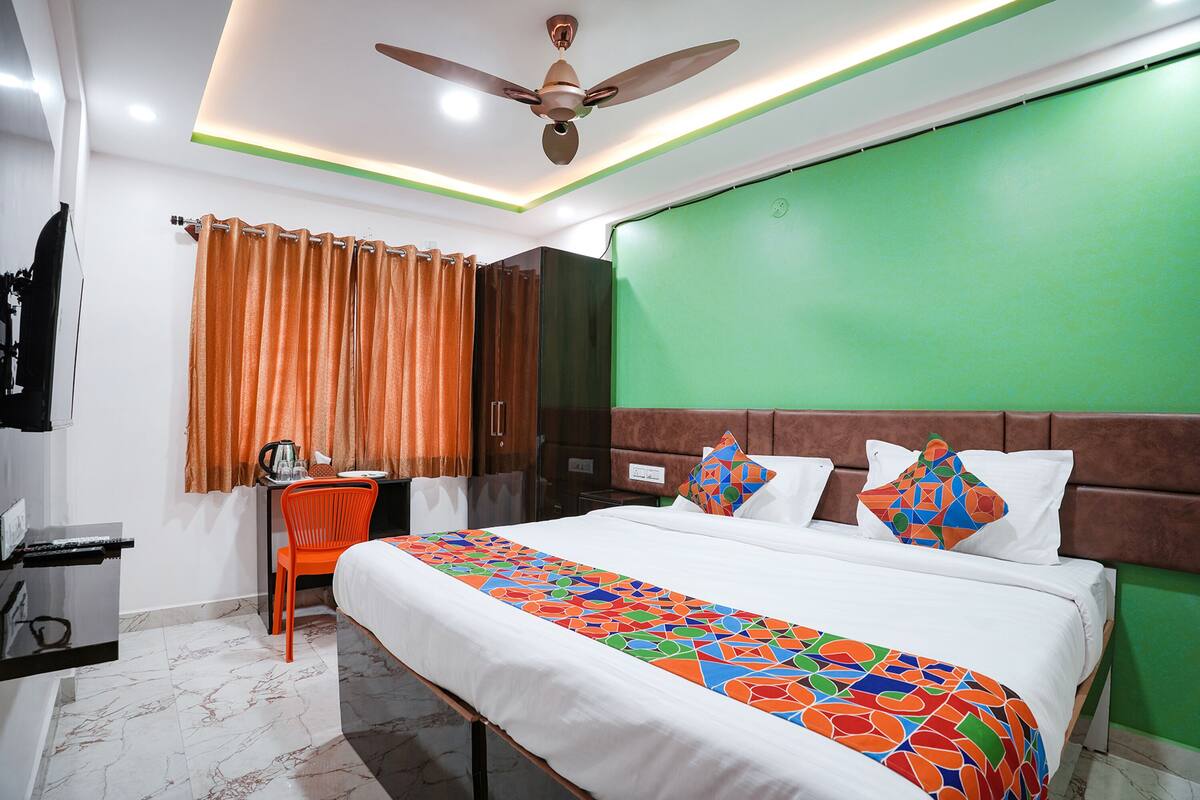 Une chambre d’hôtel avec un lit, un bureau, une chaise et un mur d’accent vert.
