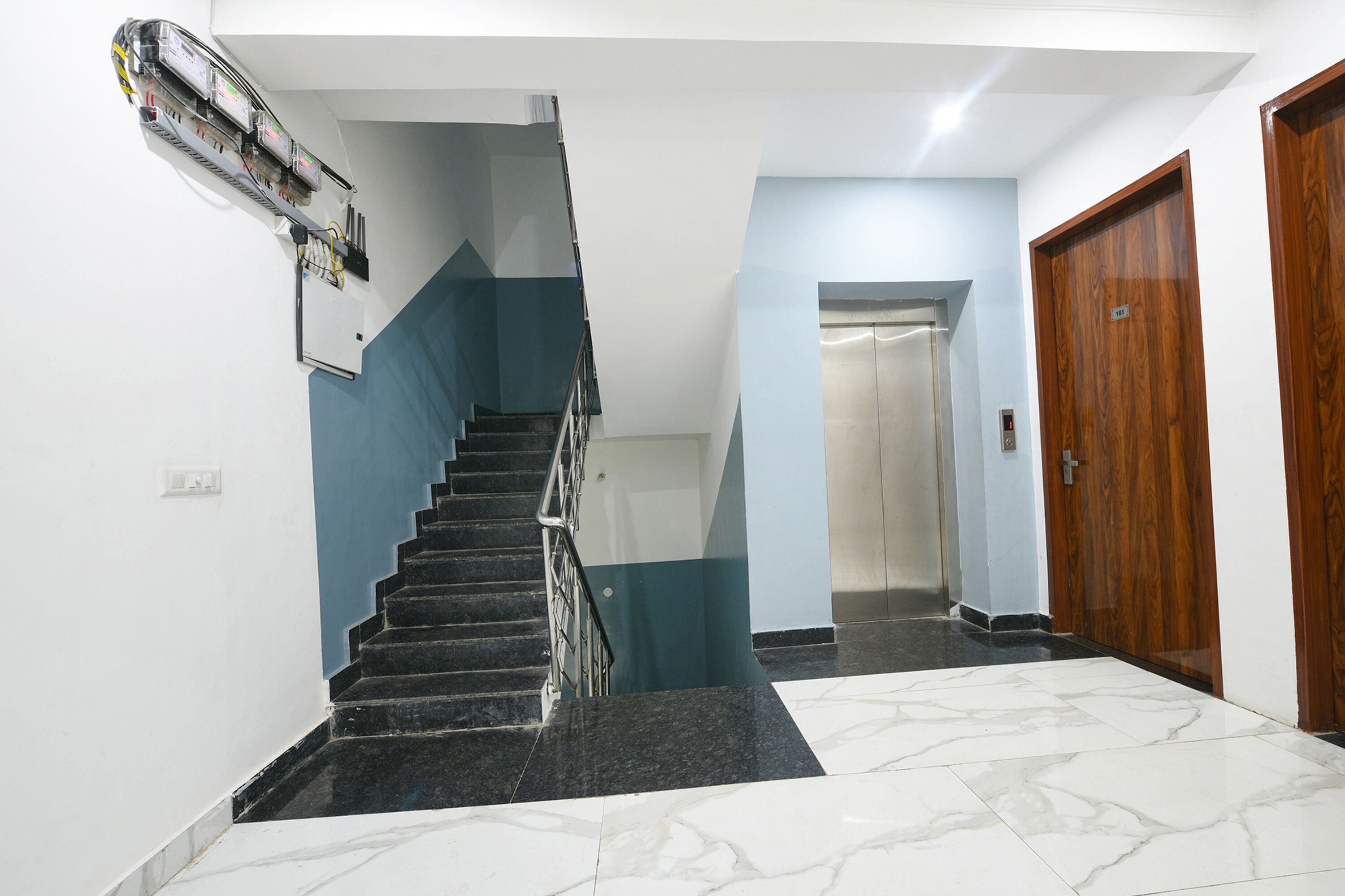 A staircase with a handrail, a wooden door, and a wall-mounted air conditioning unit.
