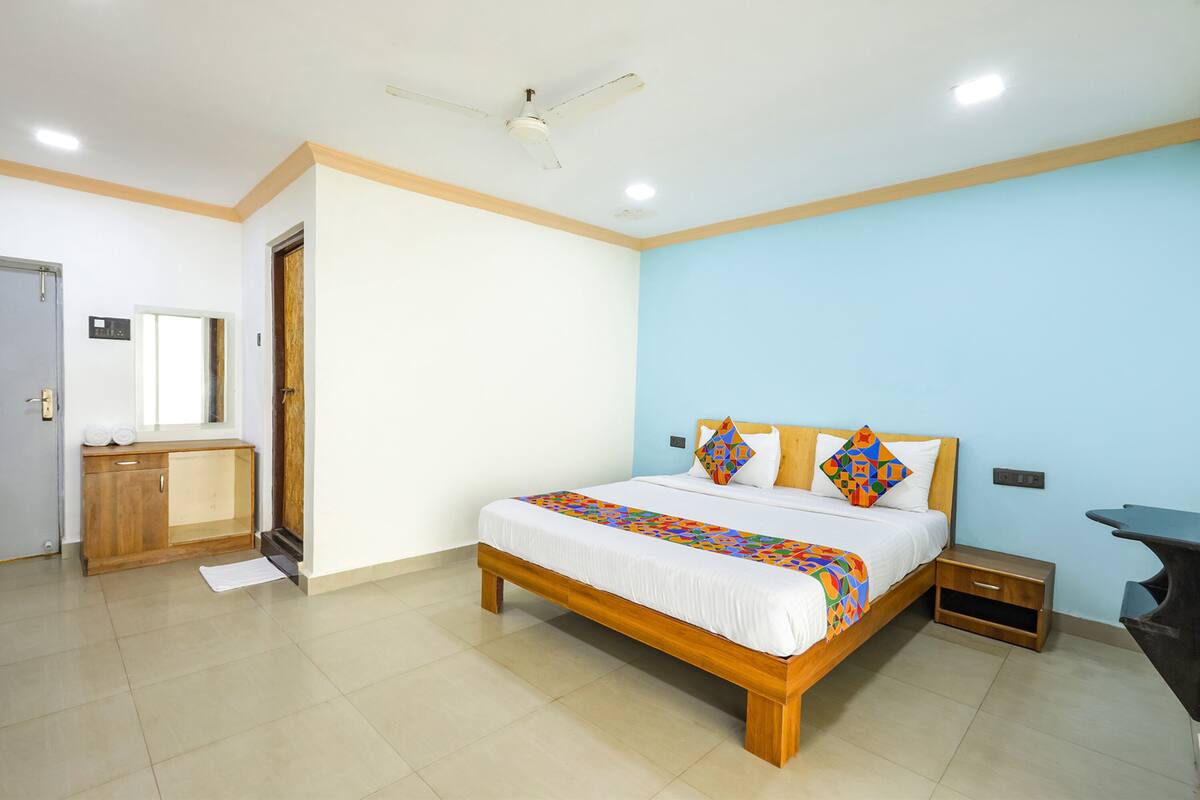 A bedroom with a bed, wooden headboard, bedside table, and a ceiling fan.