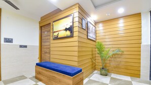 A reception area with a wooden bench, a potted plant, and framed artwork on the wall. - Fabhotel Elite (Dehradun)